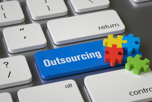Outsourcing IT services shown on a computer keyboard with puzzle pieces